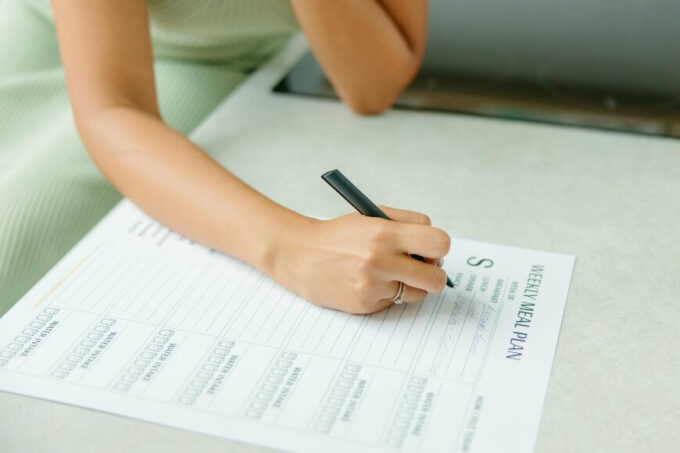 woman writing on a meal planning sheet