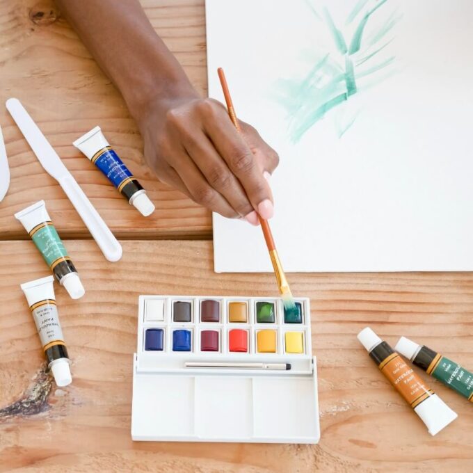 woman dipping paintbrush in paint